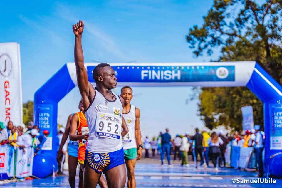 A runner celebrating victory at the Kaduna Half Marathon finish line